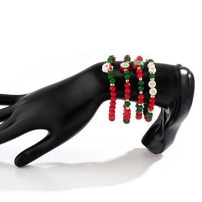 Schwarze Hand mit roten und grünen Perlenarmbändern, Weihnachtsmotive, Schmuckdisplay.