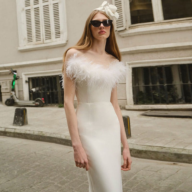 Frau in elegantem weißen Abendkleid mit Federn, Sonnenbrille, Blumenhaarschmuck, Stadtstraße.