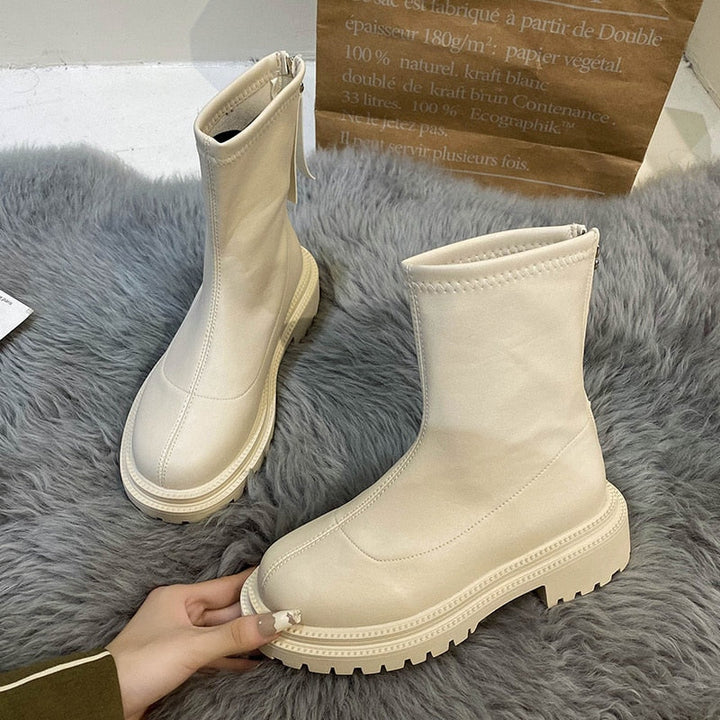 Beige Damenstiefel aus Leder mit Reißverschluss, modisch, robust, auf grauem Teppich.