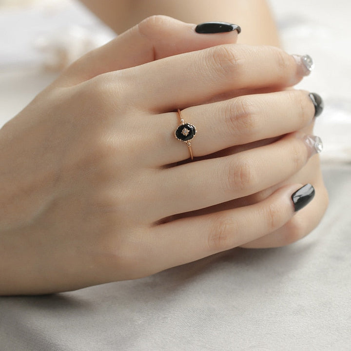 Damenhand mit schwarzem Diamantring, Roségold, elegantes Schmuckdesign.