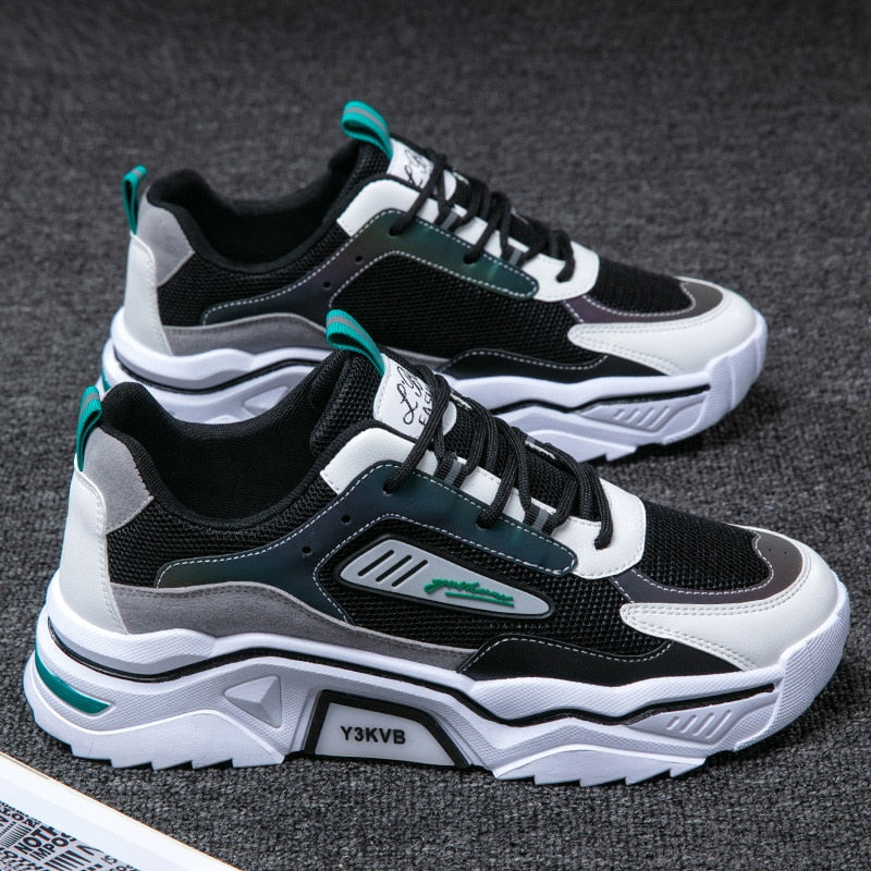 Schwarz-weiße Sportschuhe mit grünen Akzenten, atmungsaktives Mesh, rutschfeste Sohle.