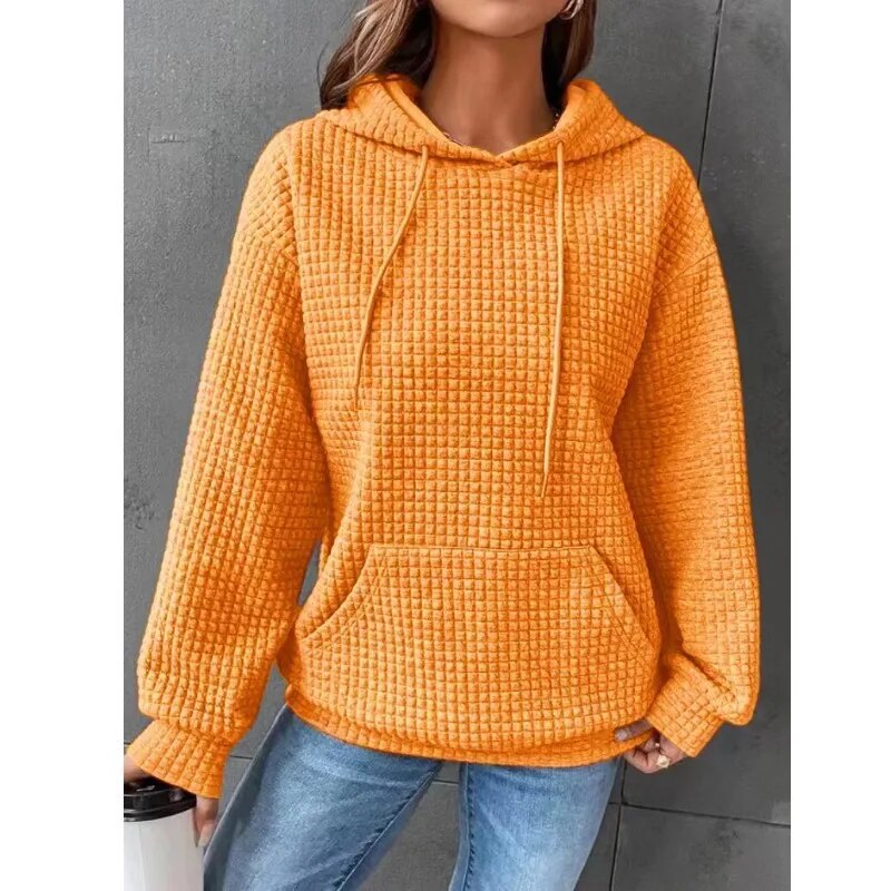 Frau in orangefarbenem Kapuzenpullover, Waffelstrick, lässig, Herbstmode, Jeans.
