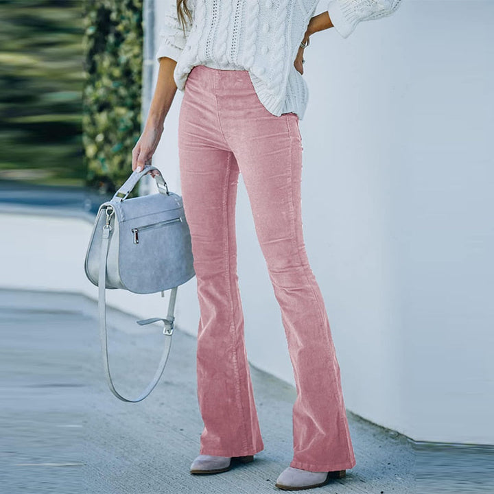 Frau in rosa Cordhose und weißem Strickpullover mit grauer Handtasche.