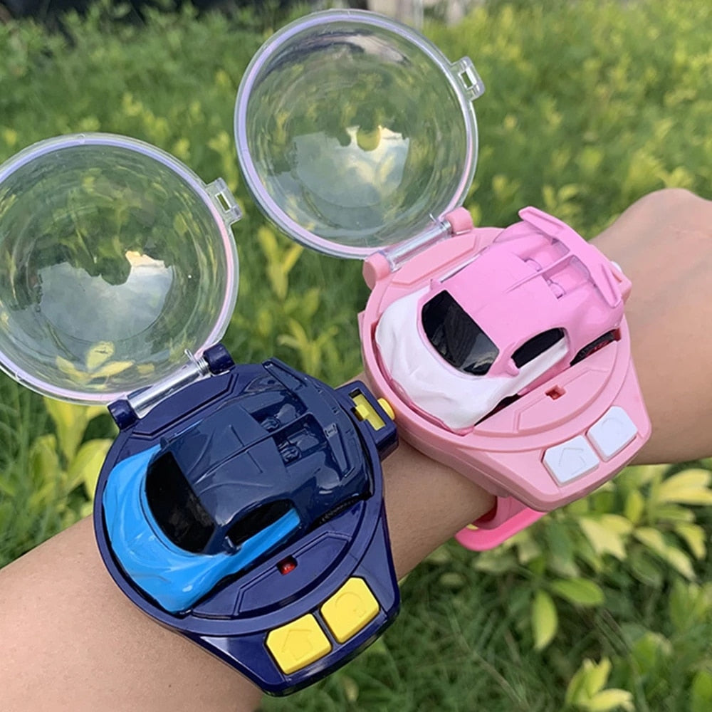 Zwei Spielzeugautos auf Armbändern, blau und rosa, mit transparenten Abdeckungen im Freien.