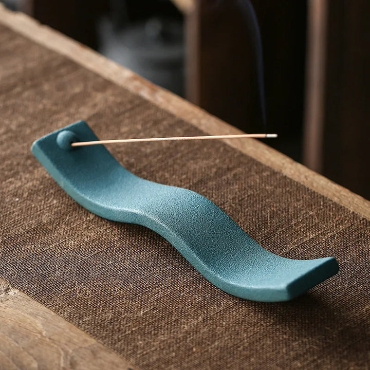 Grüner Keramik-Räucherstäbchenhalter auf Holztisch, wellenförmig, modernes Design.