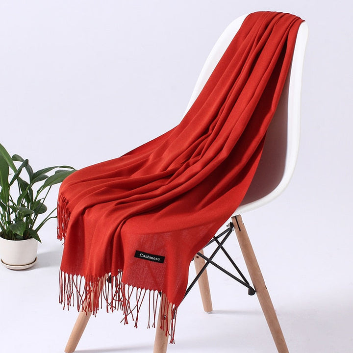 Roter Kaschmirschal auf Stuhl, weiches Material, modisches Accessoire, Wohnzimmerdekoration.
