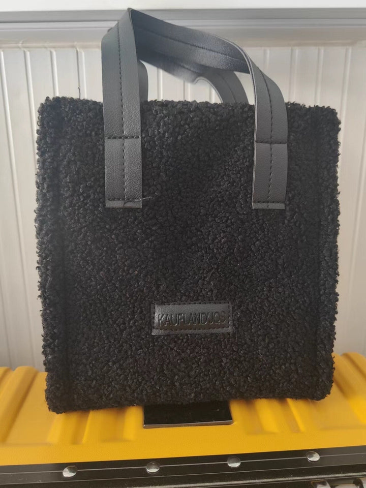 Schwarze Teddyfell-Tasche mit Ledergriffen, quadratisch, modisch, Damen-Accessoire.
