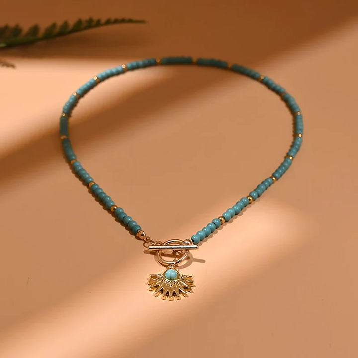 Türkisfarbene Perlenkette mit goldfarbenem Anhänger, eleganter Schmuck für Damen.