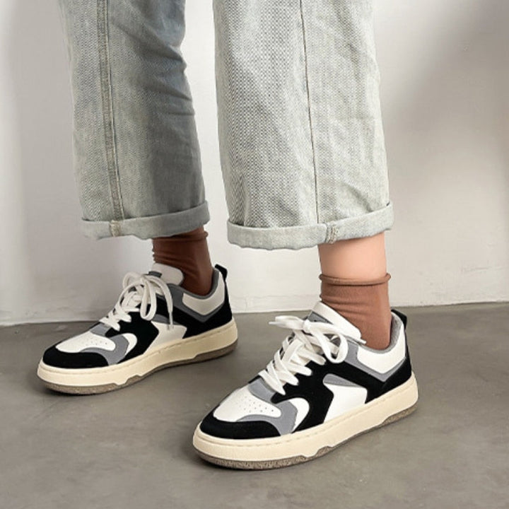 Schwarz-weiße Sneaker, Damen, Leder, lässig, modisch, mit Jeans, auf Betonboden.