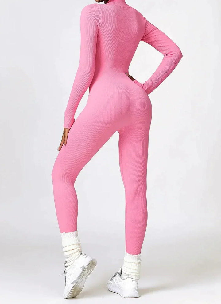 Frau in rosa nahtlosem Jumpsuit, sportlich, figurbetont, mit weißen Sneakers und Socken.