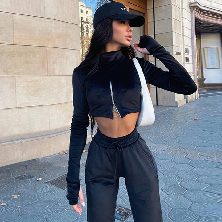Frau in schwarzem Crop-Top und Jogginghose, schwarze Mütze, weiße Tasche, Stadtstraße.