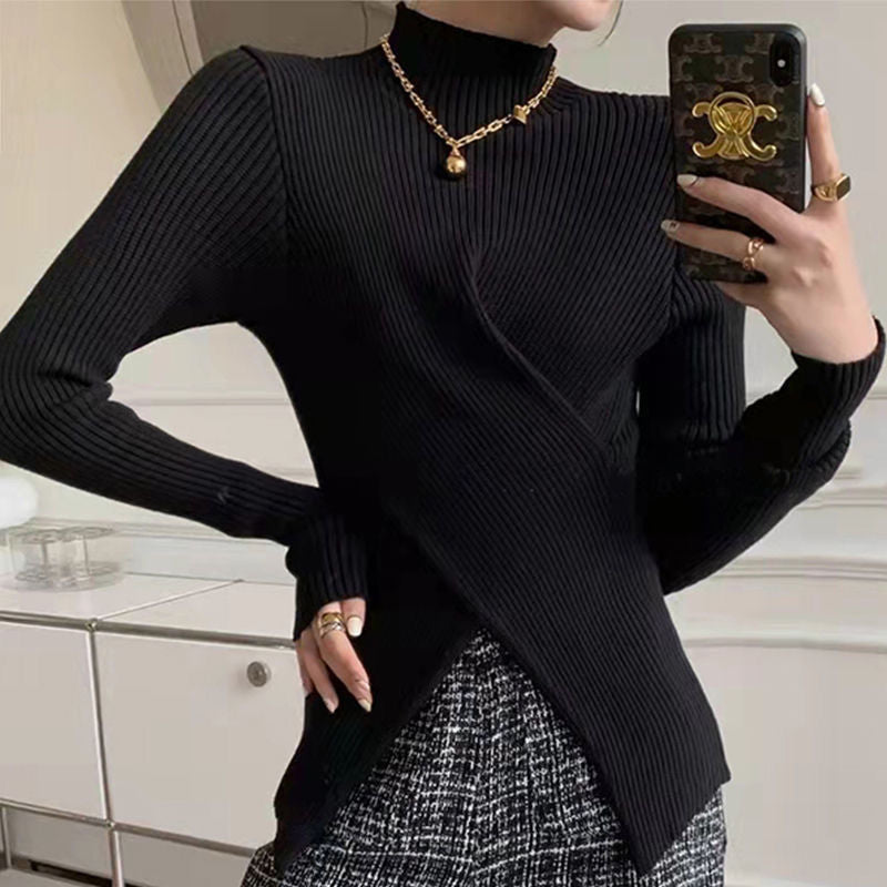 Frau in schwarzem, geripptem Pullover mit Stehkragen und goldener Halskette, modisch elegant.