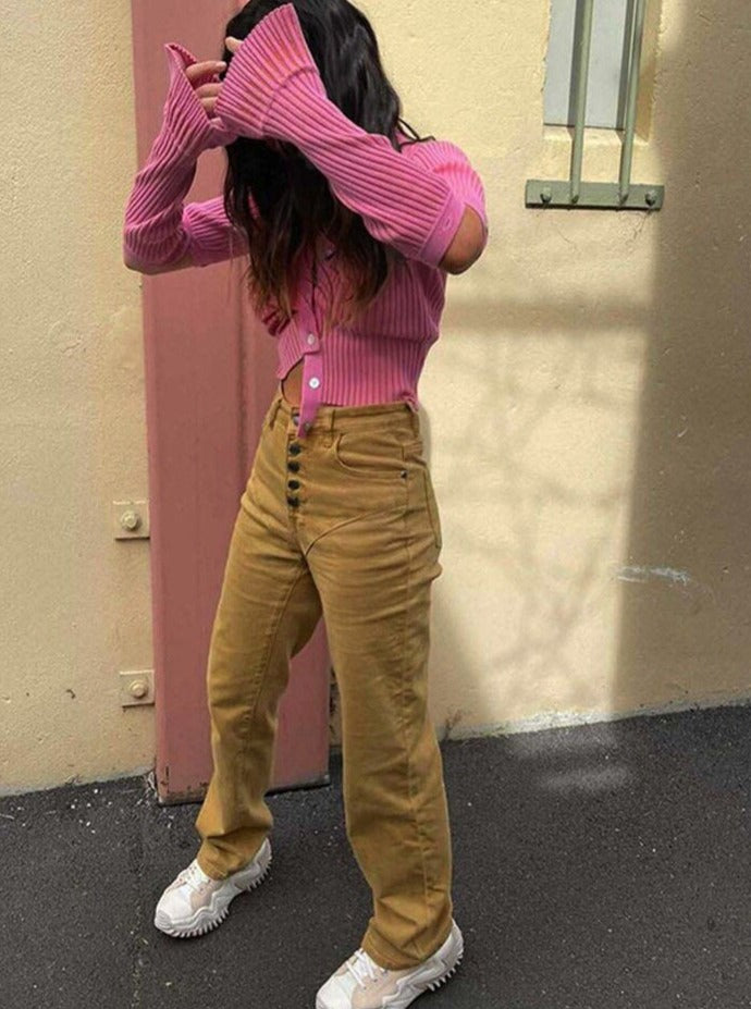 Frau in rosa Strickjacke, beige Hose, weiße Sneaker, modisch, urbaner Stil.