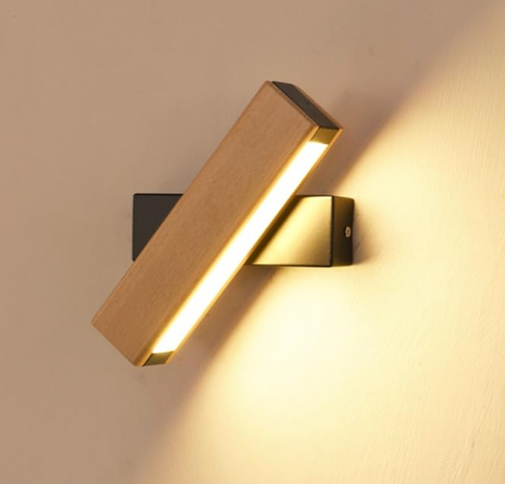 Detail rozsvícené lampy s dřevěnou lištou a černým držákem, světelný pruh a světlo šikmo na zeď. 7