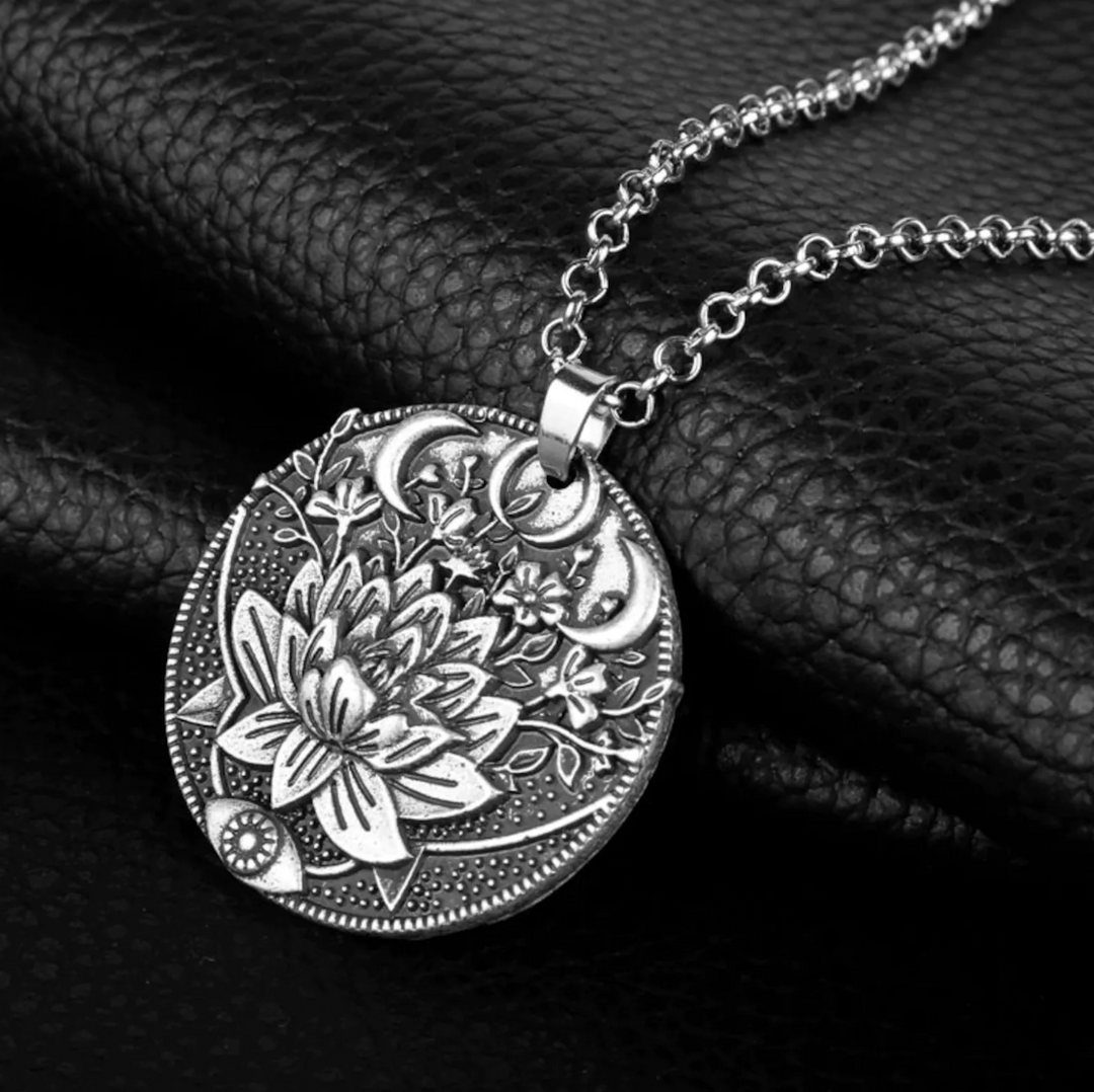 Silberne Halskette mit Lotusblumen-Anhänger, Mondmotiv, auf schwarzem Lederhintergrund.