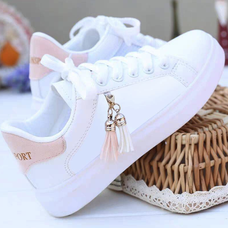 Weiße Damen-Sneaker mit rosa Akzenten und Quastenanhänger, modische Freizeitschuhe.