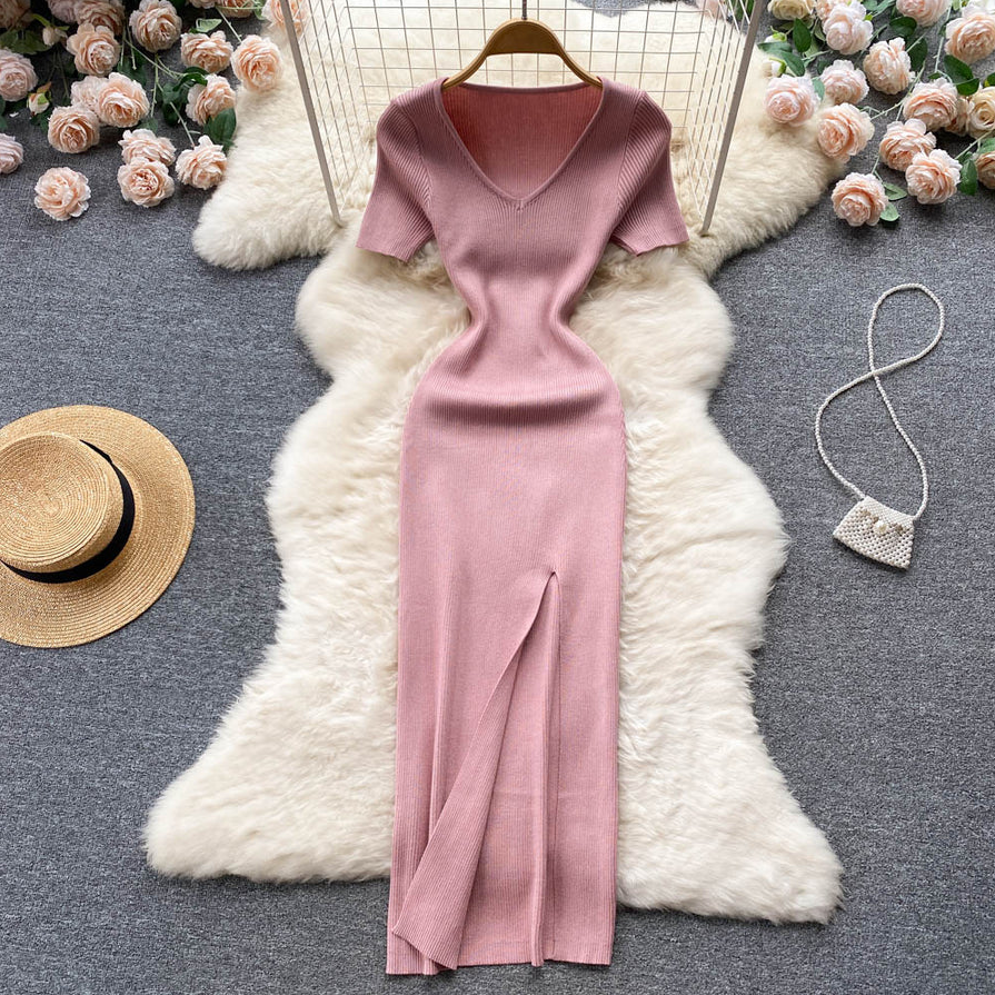 Rosa Strickkleid mit V-Ausschnitt, langem Schlitz, auf weißem Fellteppich, elegantes Design.