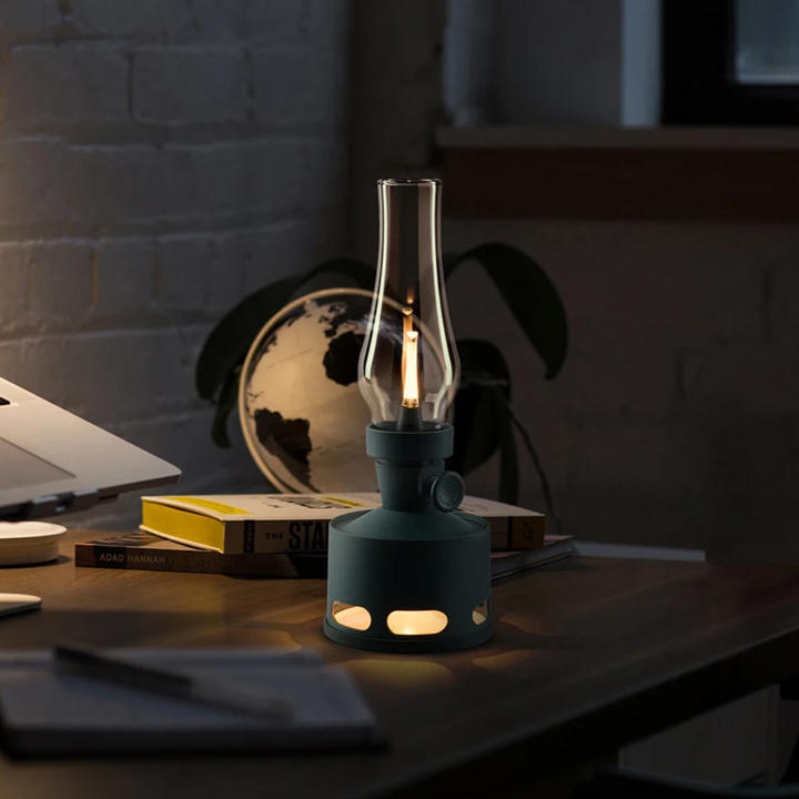 Moderne schwarze Öllampe auf Schreibtisch, beleuchtet, neben Laptop und Globus.