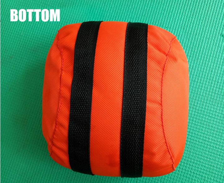 Orangefarbener Sandsack mit schwarzen Streifen auf grünem Hintergrund, Fitnesszubehör.