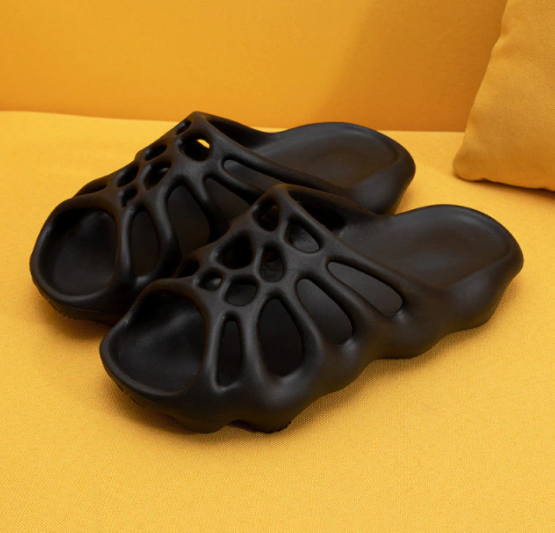Schwarze, futuristische Sandalen auf gelbem Hintergrund, atmungsaktiv, modisch, bequem.
