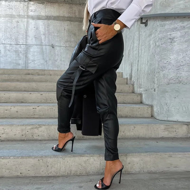 Frau in schwarzer Lederhose und High Heels auf Treppe, modisch, elegant, urbaner Stil.