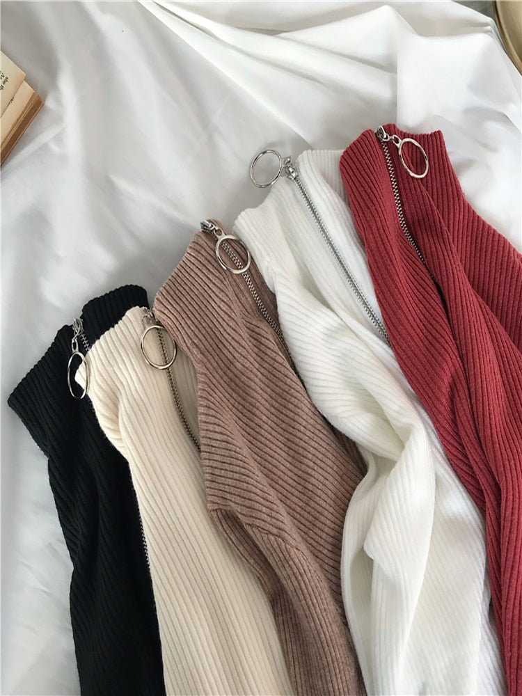 Fünf gerippte Strickjacken mit Reißverschluss in Schwarz, Beige, Braun, Weiß und Rot auf weißem Hintergrund.