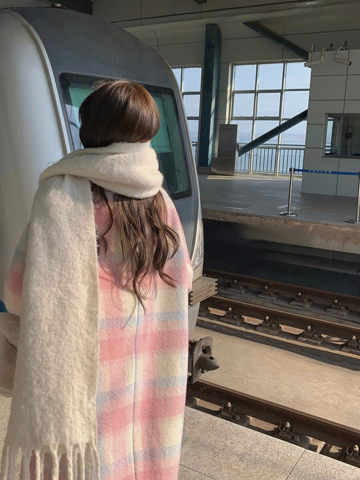 Frau mit pastellfarbenem Schal am Bahnhof vor Zug, Wintermode, Reisende, Rückansicht.