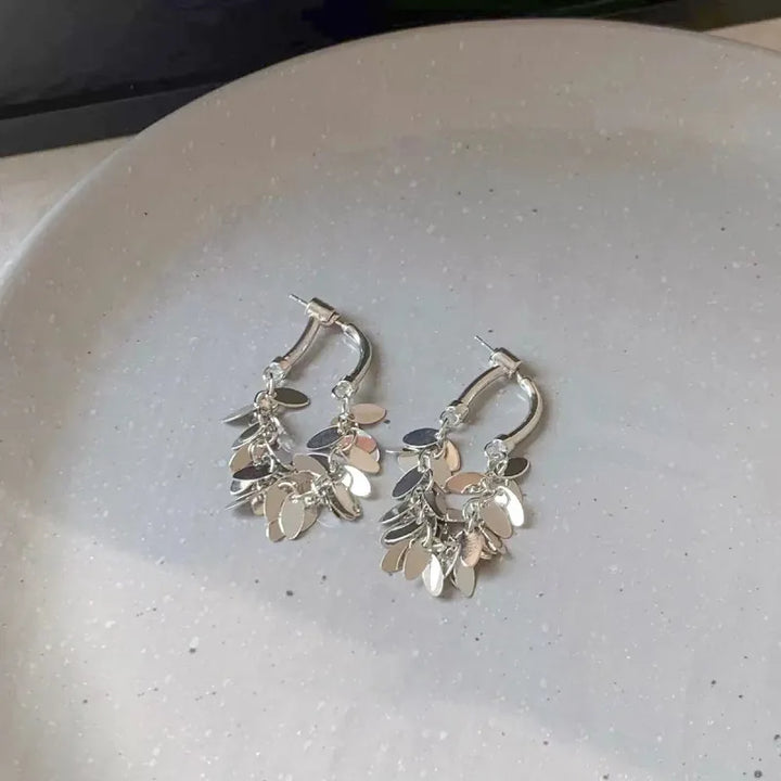 Silberne Creolen Ohrringe mit Blattanhängern, modisches Schmuckdesign, elegantes Accessoire.