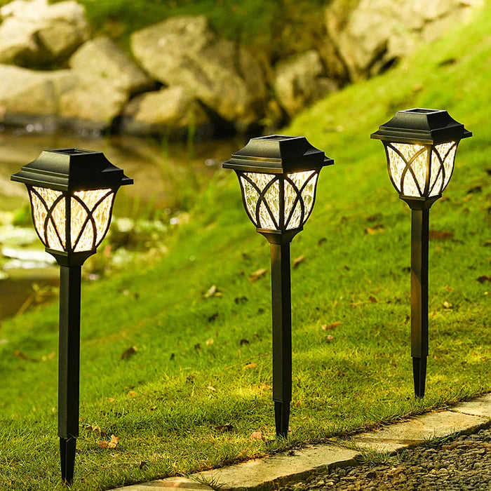 Drei schwarze Solar-Gartenleuchten auf Rasen, LED, wetterfest, energiesparend.