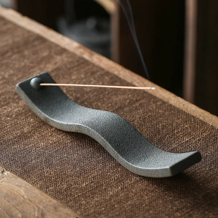Schwarzer Keramik-Räucherstäbchenhalter, wellenförmig, auf Holztisch, modernes Design.