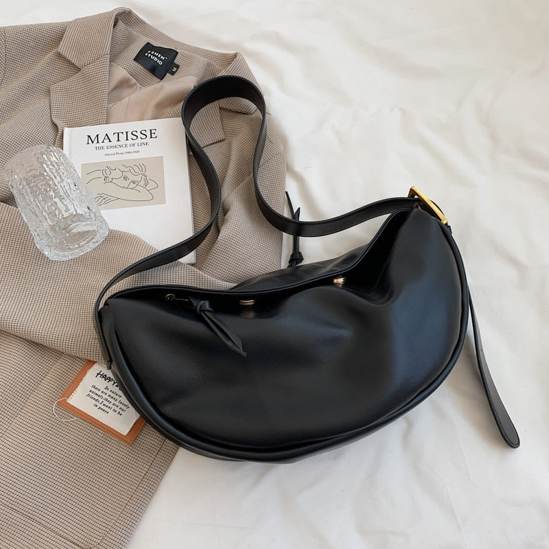 Schwarze Lederhandtasche auf beigem Blazer, modernes Design, elegantes Accessoire.