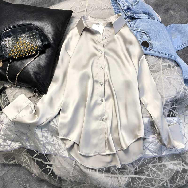 Seidenbluse Damen beige, elegant, langarm, Knopfleiste, auf Bett mit Jeansjacke und Tasche.