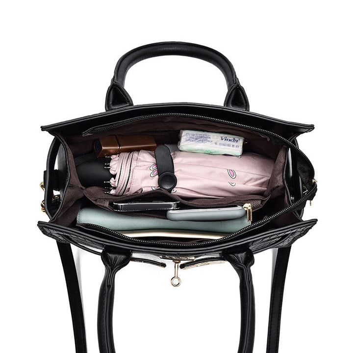 Schwarze Lederhandtasche, offen, mit Regenschirm, Geldbörse, Kosmetik, Smartphone, Damenmode.