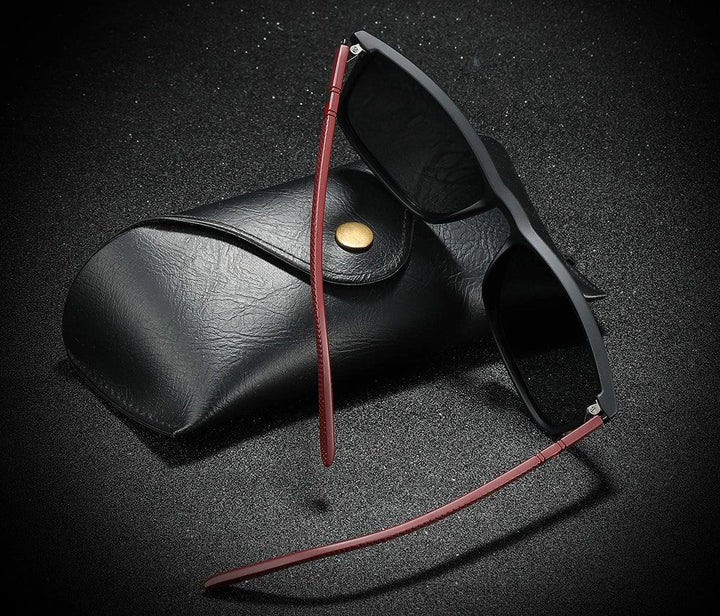 Schwarze Sonnenbrille mit rotem Bügel und Etui, modisches Accessoire, UV-Schutz.
