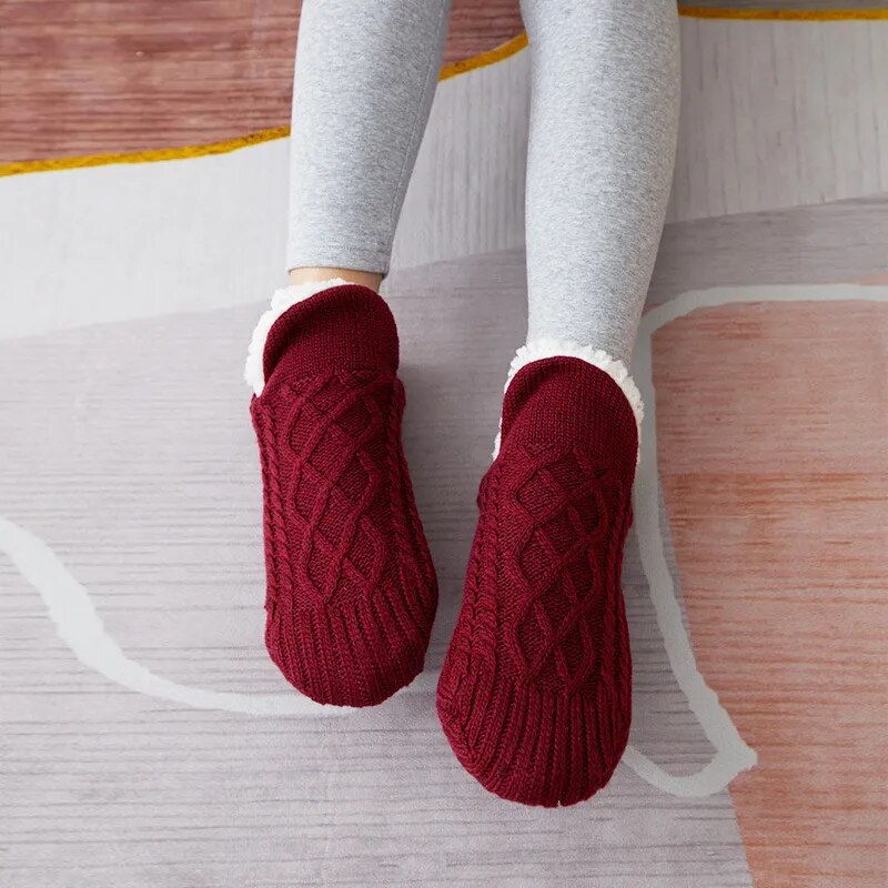 Rote Strickhausschuhe auf grauem Teppich, gemütlich, warm, Damenmode, Winteraccessoire.