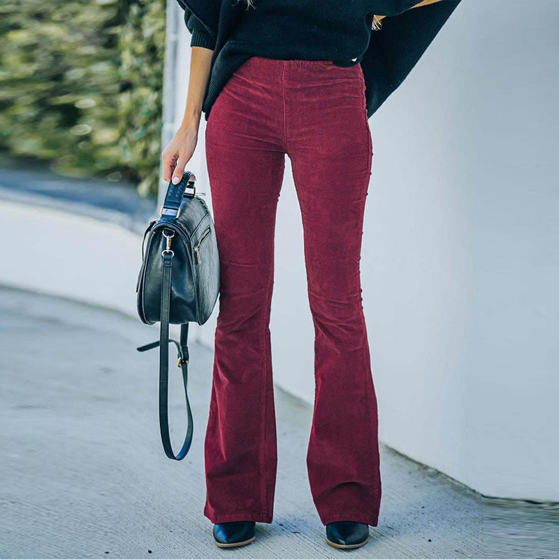 Frau in roter Schlaghose aus Cord, schwarze Tasche, modischer Herbstlook.