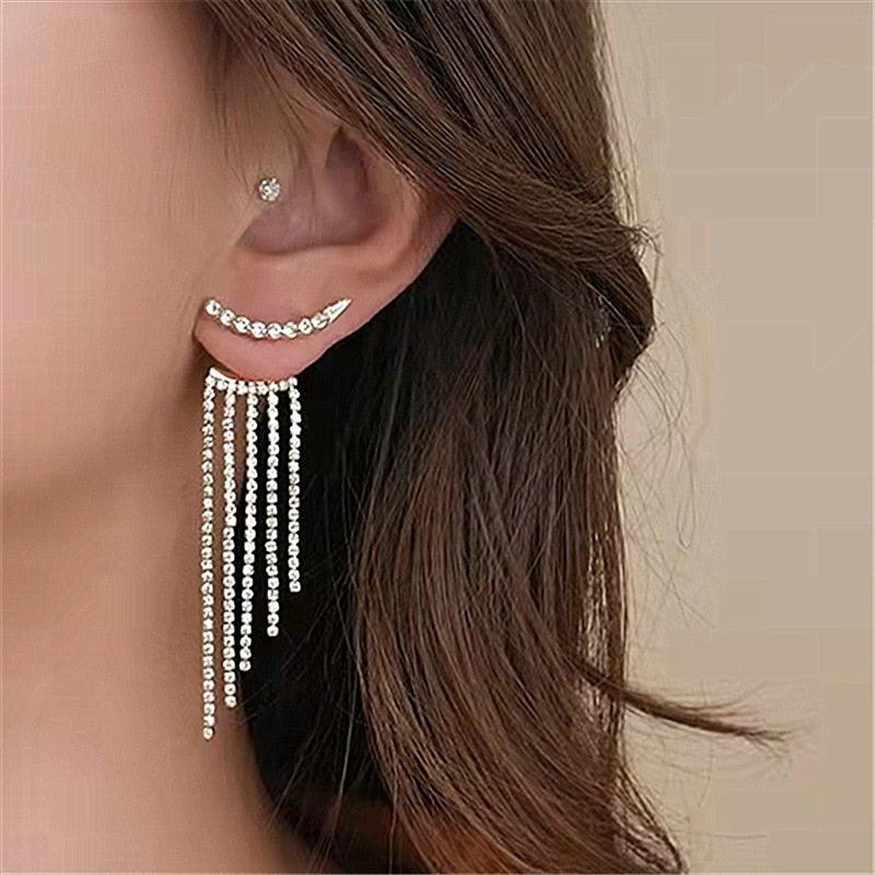Frau mit eleganten, langen Strass-Ohrringen, silberfarben, modisches Schmuckdesign.