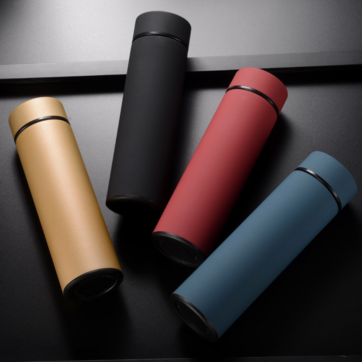 Vier Thermosflaschen in Schwarz, Rot, Blau und Gold auf schwarzem Hintergrund.