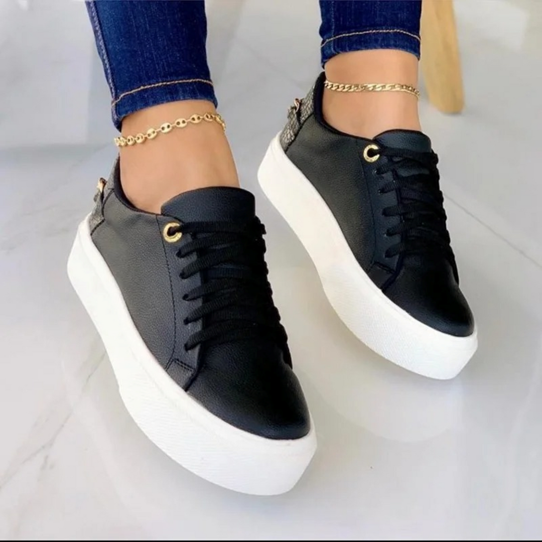 Schwarze Damen-Sneaker aus Leder mit weißer Sohle und goldener Kette, modisch, bequem.