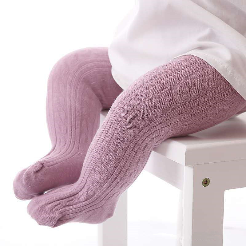 Baby in rosa Strumpfhose aus Baumwolle auf weißem Stuhl, gemütliche Kinderbekleidung.