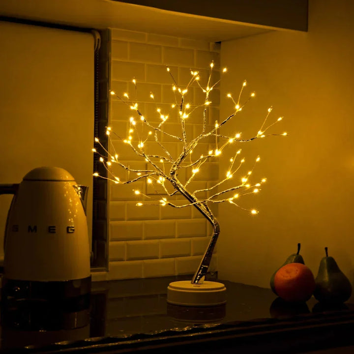 Svítící stromová lampa na kuchyňské lince před zdí z kachlíků, vedle rychlovarné konvice a ovoce 5