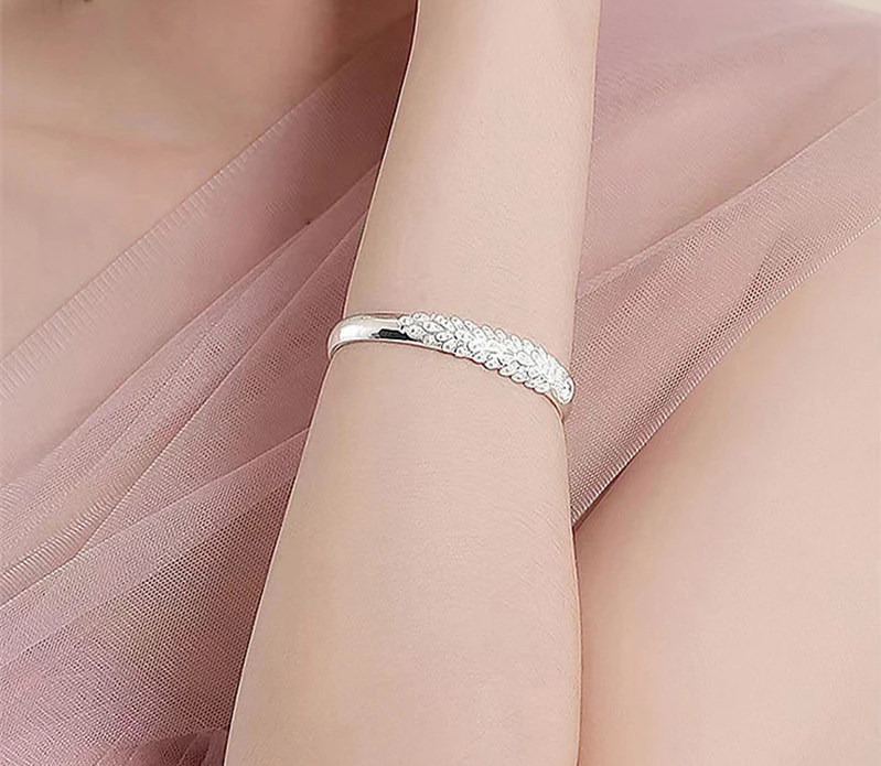 Silberarmband mit geflochtenem Design auf Frauenarm, eleganter Schmuck, Nahaufnahme.