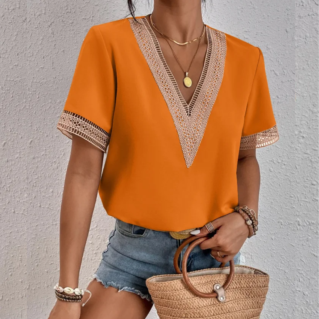 Frau in orangefarbener Bluse mit V-Ausschnitt, Jeansshorts, Strohtasche, Sommermode.