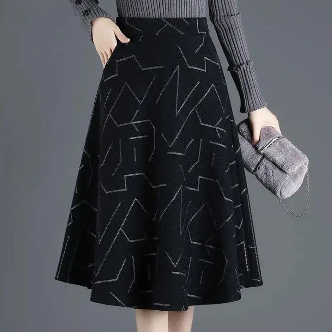 Damen A-Linien-Rock schwarz mit geometrischem Muster, grauer Pullover, graue Handtasche.