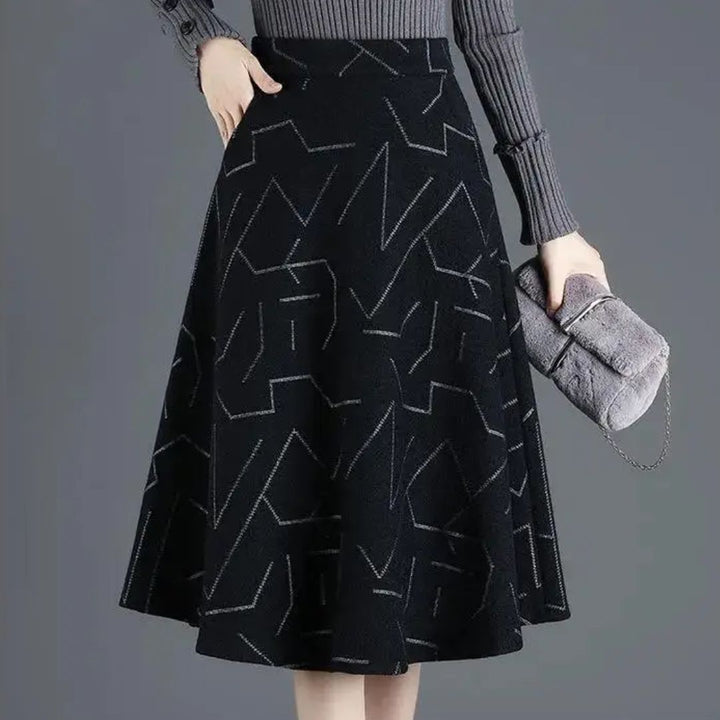 Damen A-Linien-Rock schwarz mit geometrischem Muster, grauer Pullover, graue Handtasche.