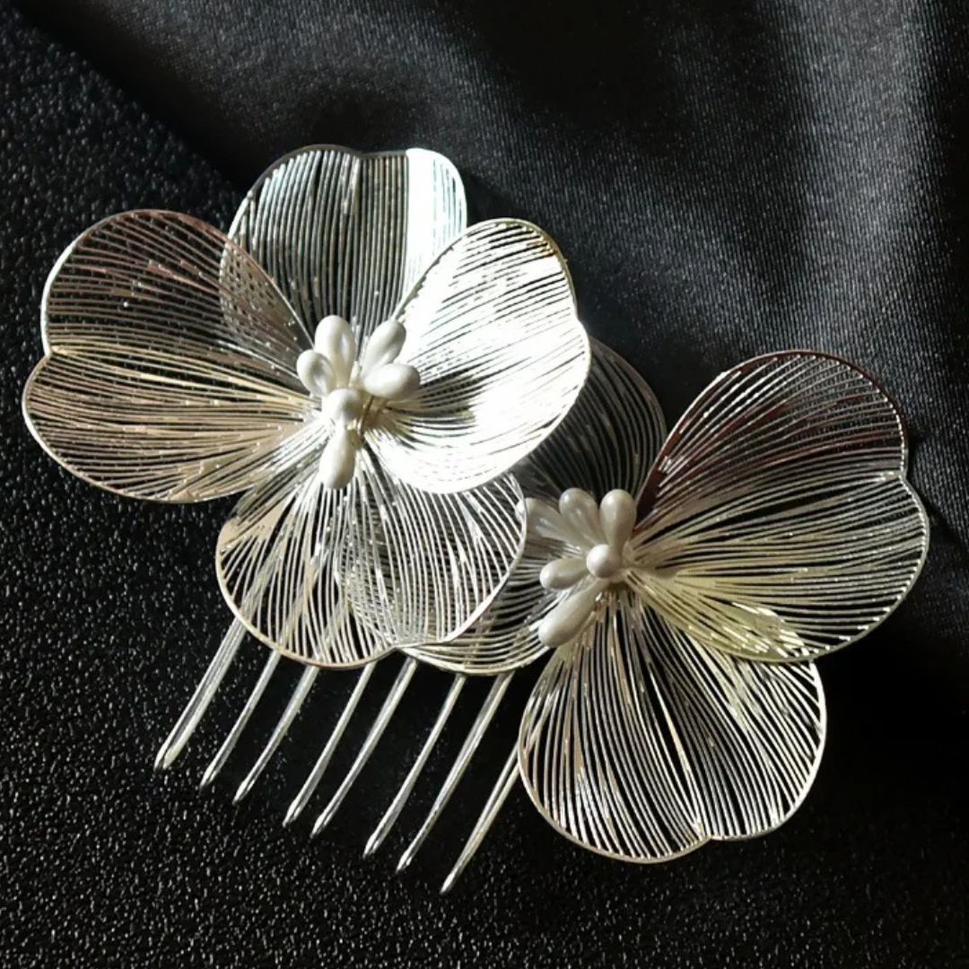 Silberne Haarspange mit filigranen Blumen, Perlenakzenten, elegantes Accessoire auf schwarzem Stoff.