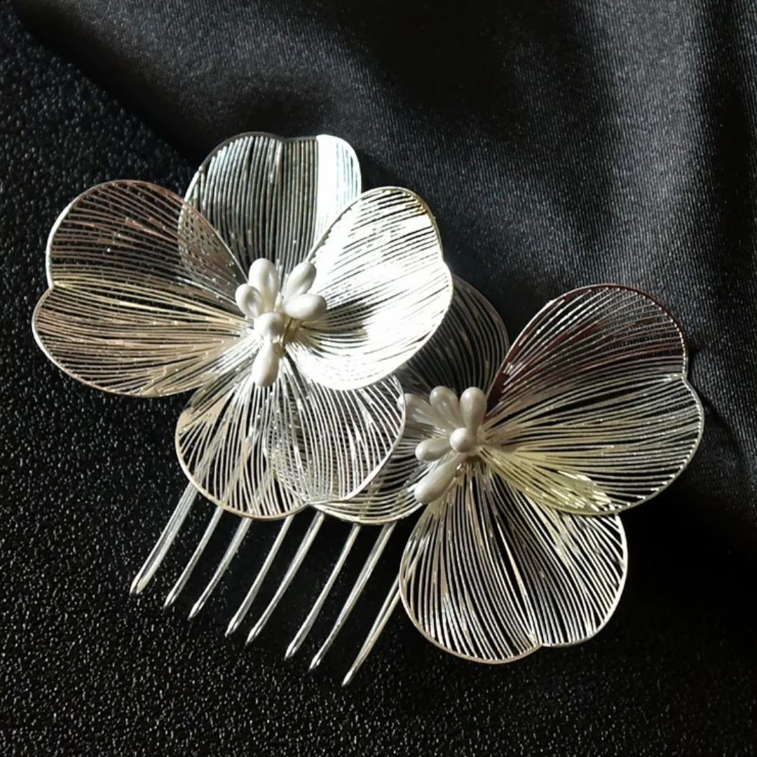 Silberne Haarspange mit Blumenmotiv, filigranem Design und Perlendetails auf schwarzem Hintergrund.