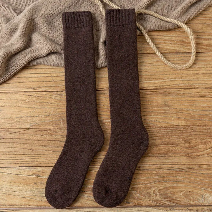 Braune Wollsocken auf Holzboden, warme Strümpfe, gemütliche Winterkleidung, modische Accessoires.