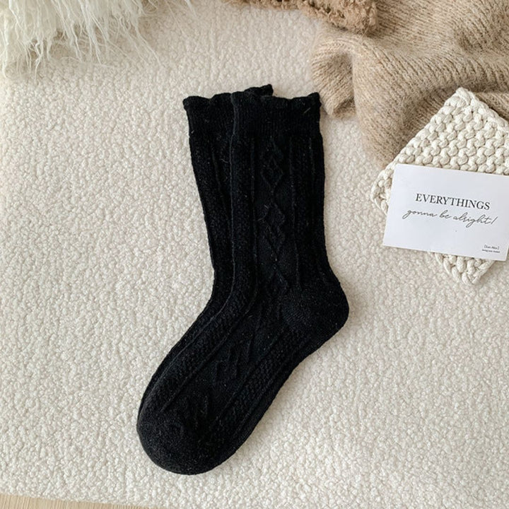 Schwarze Stricksocken aus Wolle auf beigem Hintergrund, gemütlich, warm, modisch.