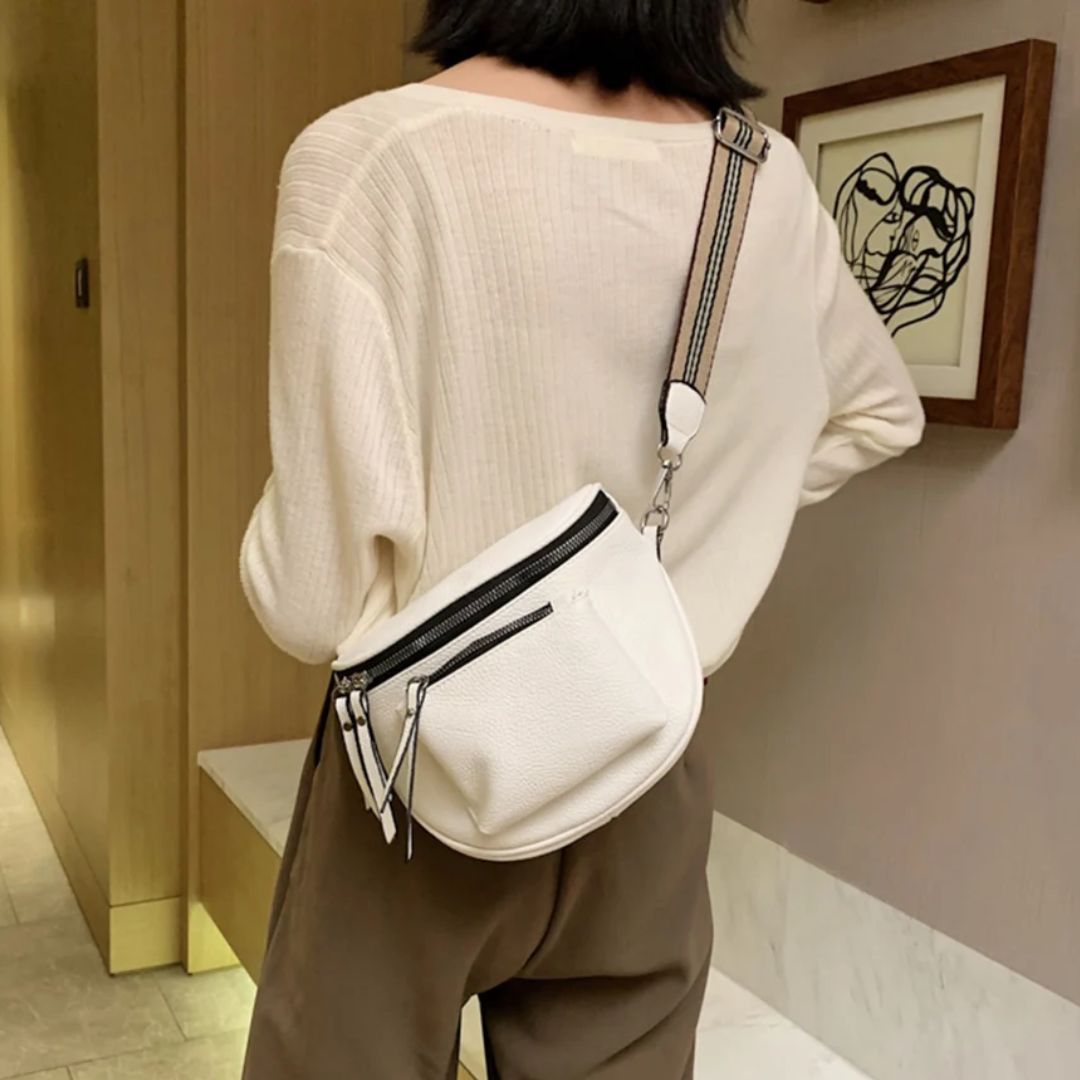 Frau mit weißer Umhängetasche, lässiger Stil, beiger Pullover, braune Hose, moderne Mode.